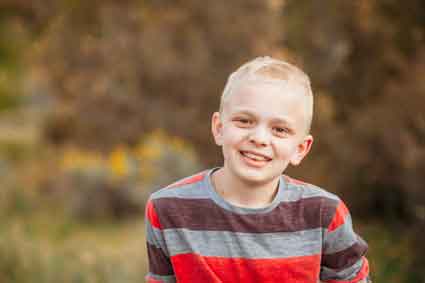 boy with neurofibromatosis type 1 with very short hair, outside, smiling