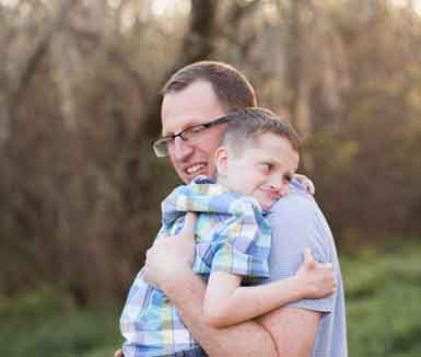 Father holds son with genetic condition as they tightly hug
